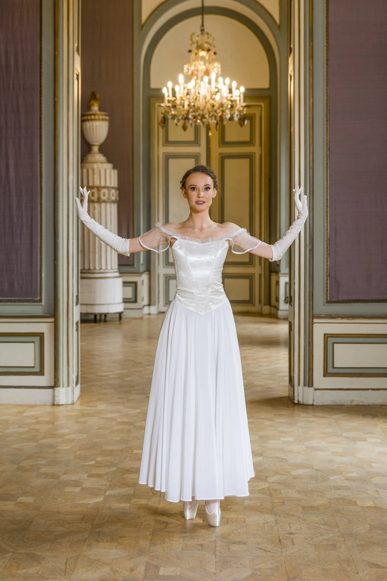 Balletttänzerin im weißen Kleid vor einer Flügeltür
